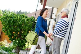 Ambulante Pflegekraft wird von Seniorin zuhause begrüßt